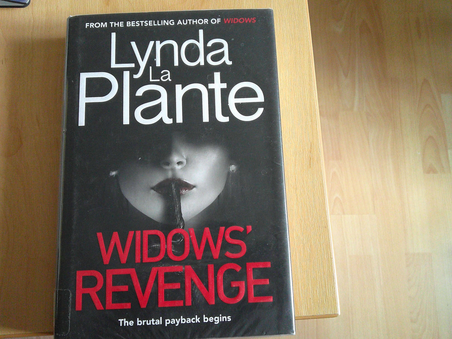 Lynda La Plante Widows Revenge book cover featuring a mysterious woman with a dark background