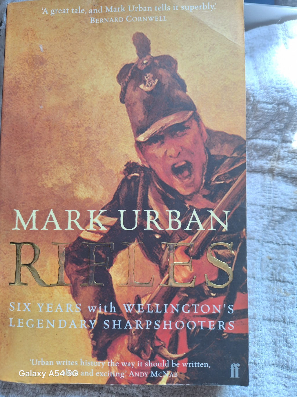 The Rifles book cover by Mark Urban featuring a soldier with a determined expression and historical military uniform