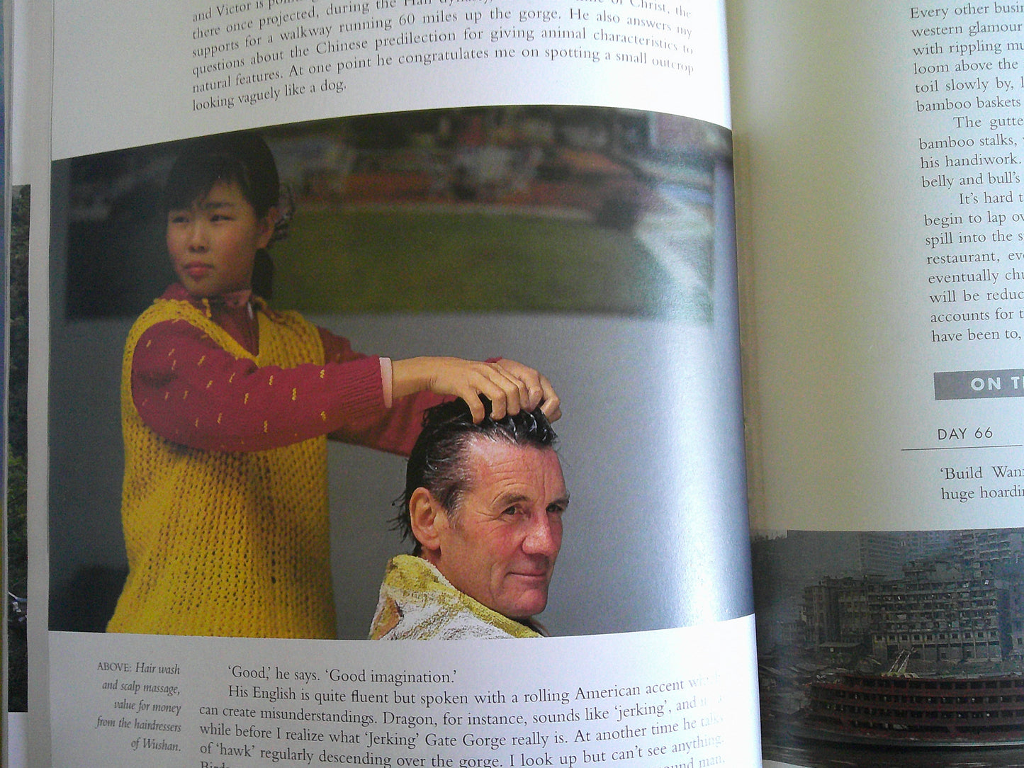 Inside page of Michael Palin travel documentaries book featuring a child styling a man's hair in vibrant setting