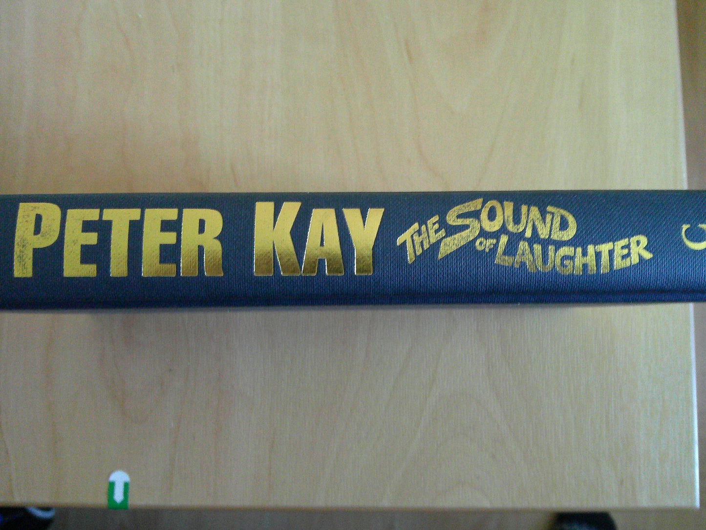 Spine of 'The Sound of Laughter by Peter Kay' book with gold lettering on a navy background