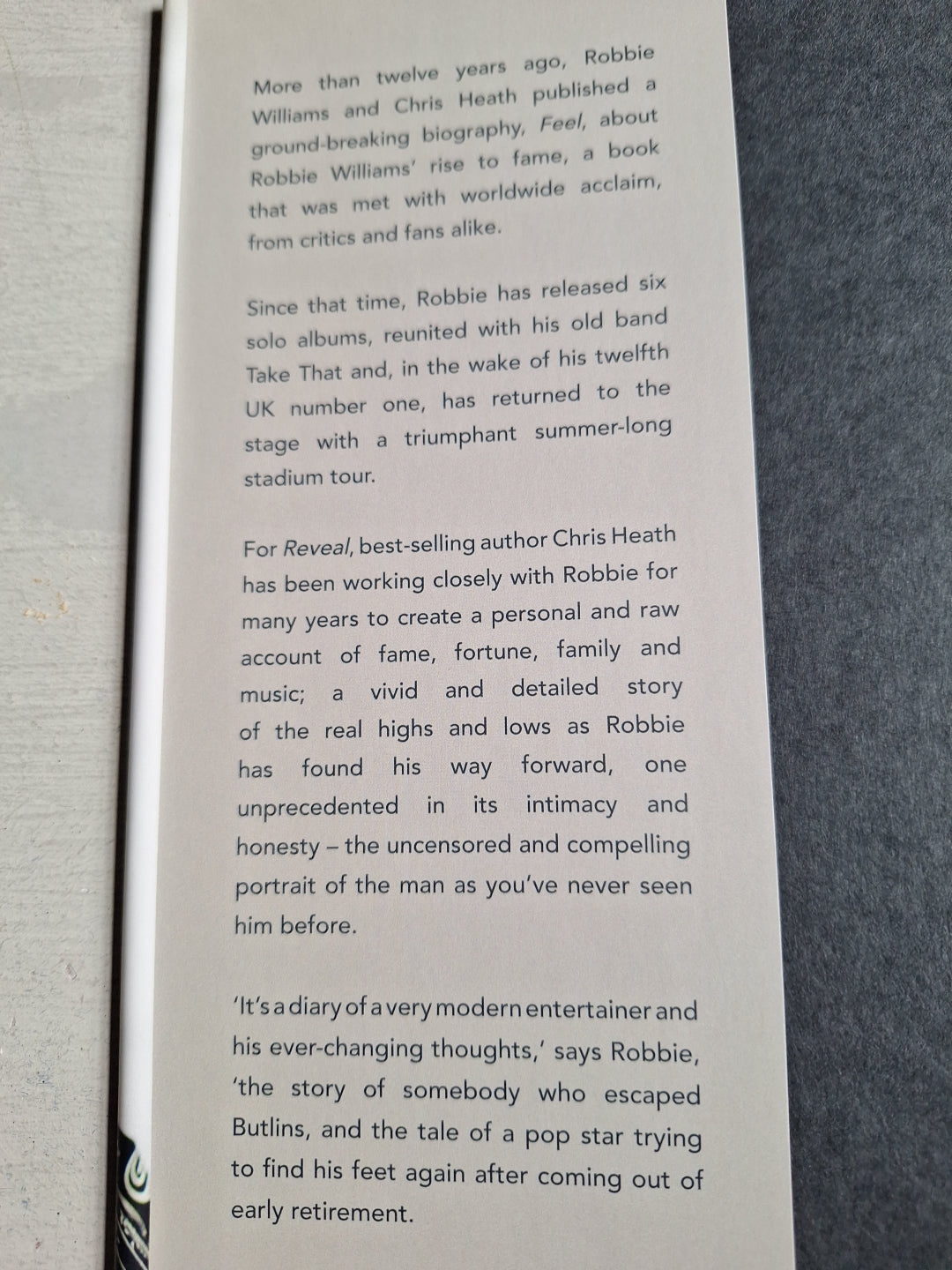 Page from Robbie Williams biography book detailing his career, albums, and personal story