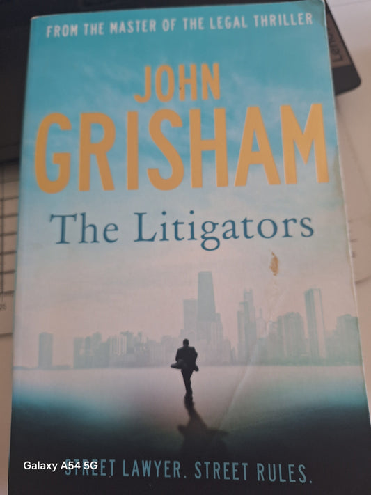 Used John Grisham The Litigators novel featuring a city skyline with a lone figure walking